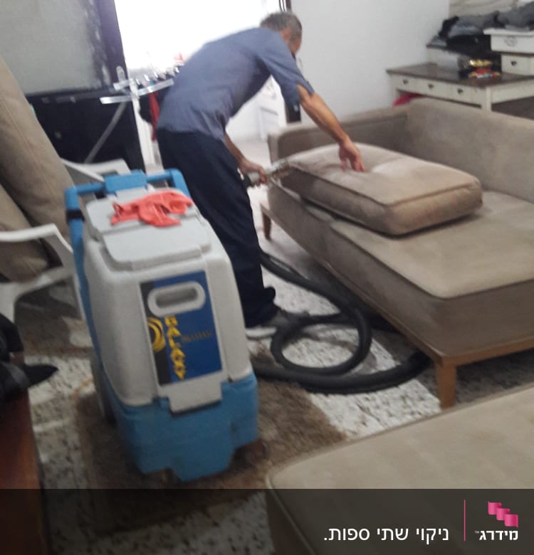 אדם מנקה ספה עם מכונת ניקוי מקצועית